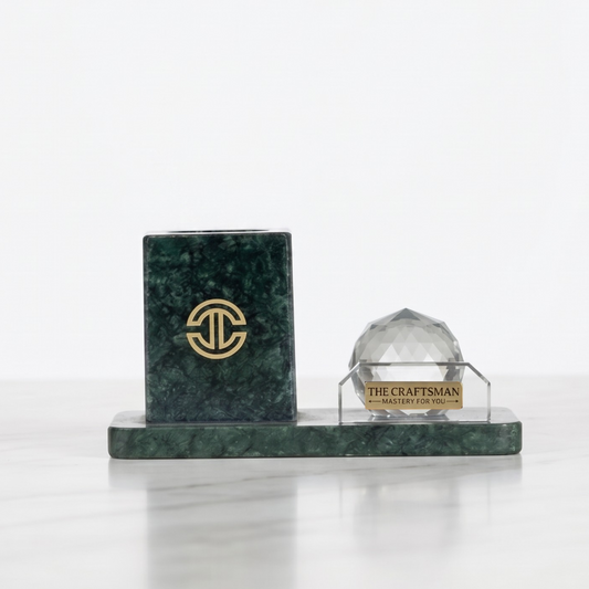 Green marble pen holder along side a crystal sphere kept on white background