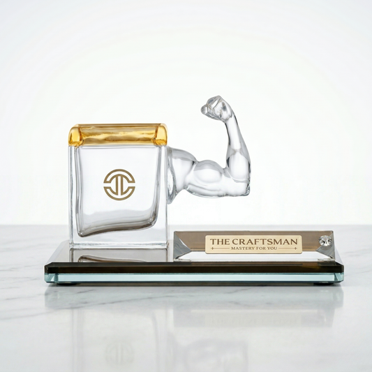 Glass pen stand of a strong arm with a yellow top lid on a white background kept on a marble surface