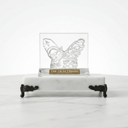 Butterfly-shaped crystal on a marble stand with 'The Craftsman' branding.