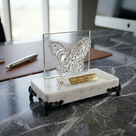 Decorative butterfly sculpture on a marble base with 'The Craftsmen' label on a desk.