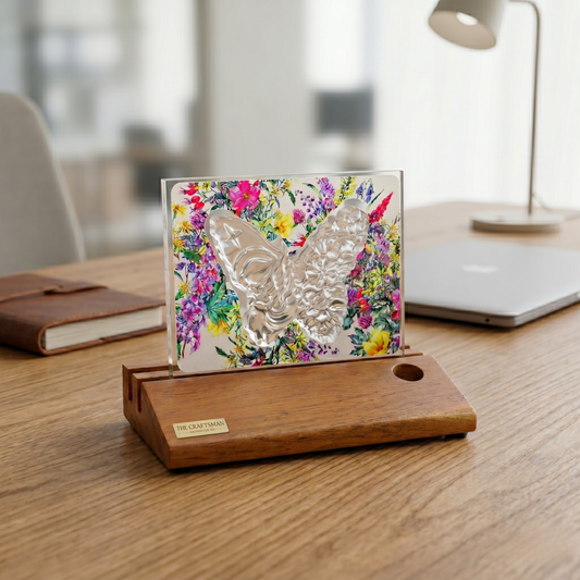 Decorative angel butterfly with floral design backdrop on glass with wooden base kept on the wooden table