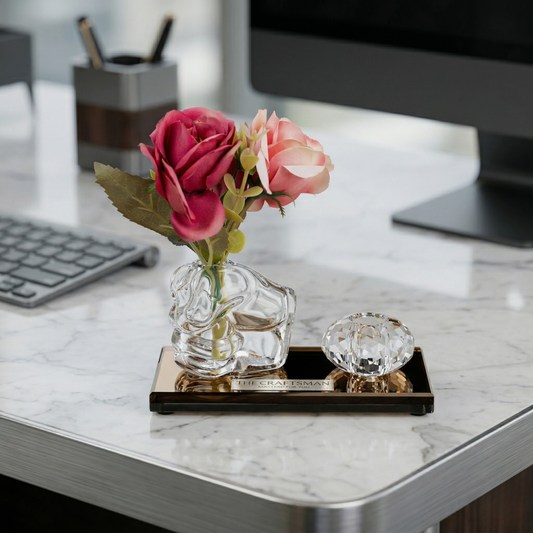 Decorative crystal glass pen stand vase with pink flowers on a glass base kept on marble surface