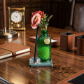 Green glass vase filled with fragrance beads with flowers placed on a green marble with crystal pen stand