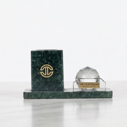 Green marble pen holder along side a crystal sphere kept on white background
