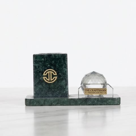 Green marble pen holder along side a crystal sphere kept on white background