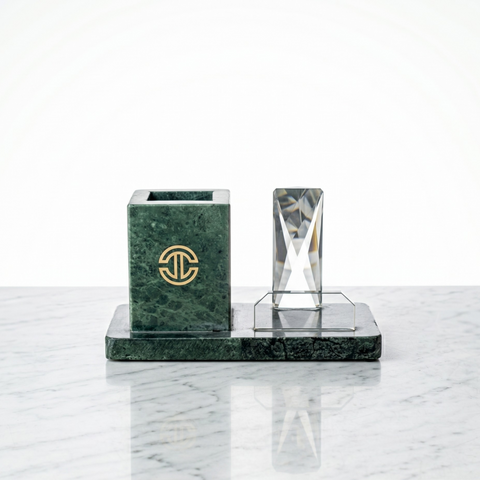 Green marble pen holder and clear crystal object doubles as a mobile holder on a white marble surface