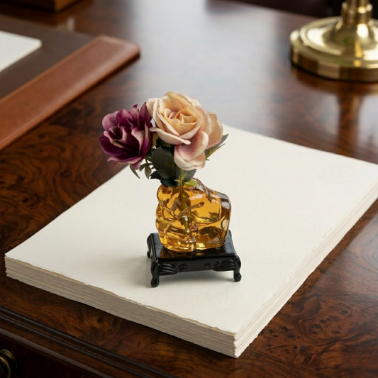 Glass human fist shaped flower vase paperweight placed on black glass base with traditional foots