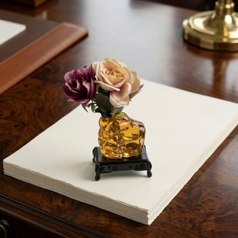 Glass human fist shaped flower vase paperweight placed on black glass base with traditional foots