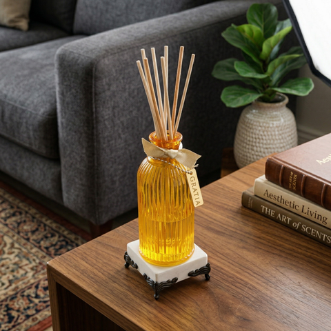 Yellow diffuser bottle with reeds on a wooden table in a living room setting.