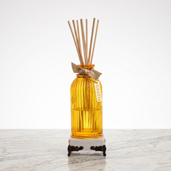 Yellow diffuser bottle with wooden sticks on a marble base with lemon fragrance