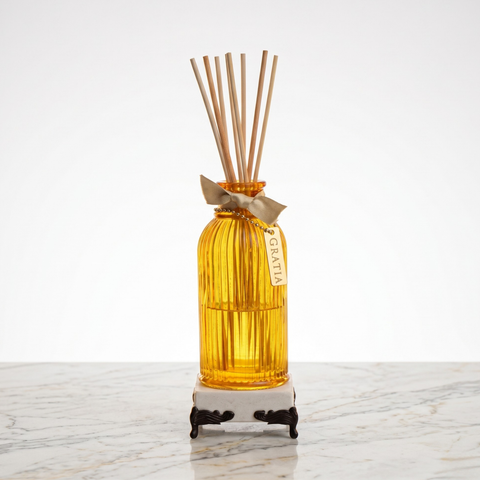 Yellow diffuser bottle with wooden sticks on a marble base with lemon fragrance