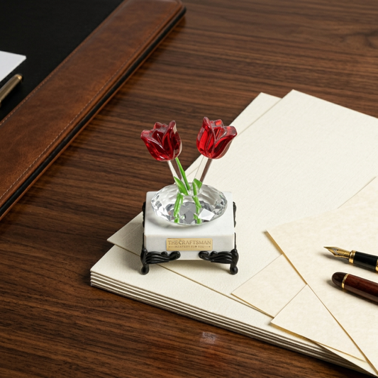 Marble base paper weight with two crystal tulip flowers with round clear glass stem growing from the marble with traditional legs kept on the above of papers on the wooden table