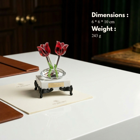 Decorative item with red tulips on a marble base on a table.